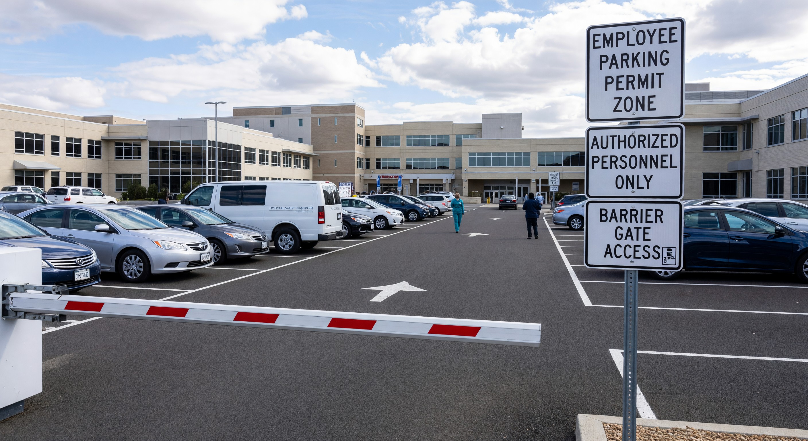 Hospital employee parking lot with permit zone signage and barrier gate access