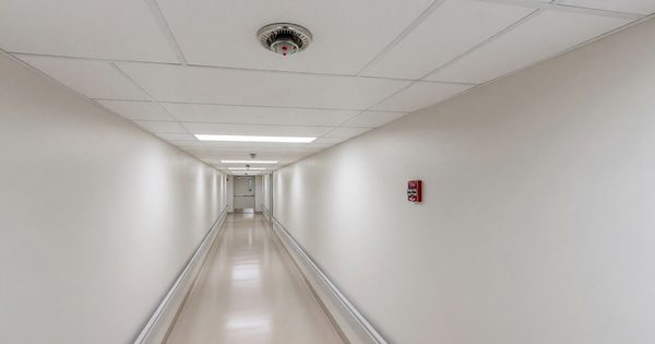 Hospital sprinkler head in clinical corridor with fire alarm pull station visible in background
