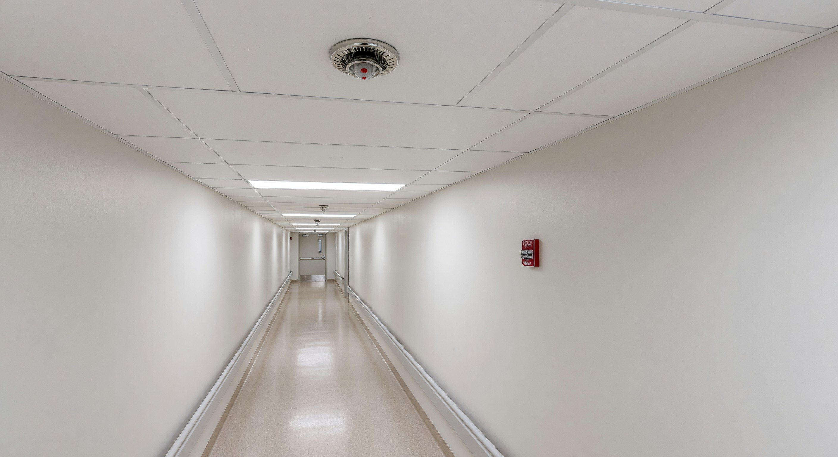 Hospital sprinkler head in clinical corridor with fire alarm pull station visible in background