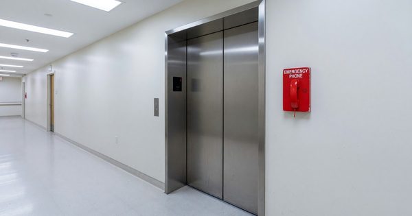 Hospital elevator lobby with wide bariatric elevator and emergency phone panel visible