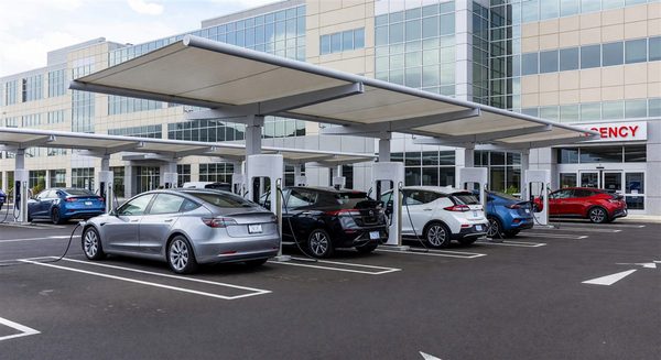 Hospital parking lot with EV charging station canopies and multiple electric vehicles charging