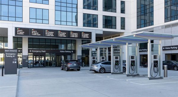 Hospital entrance with modern parking guidance system, EV charging canopies, and clear wayfinding
