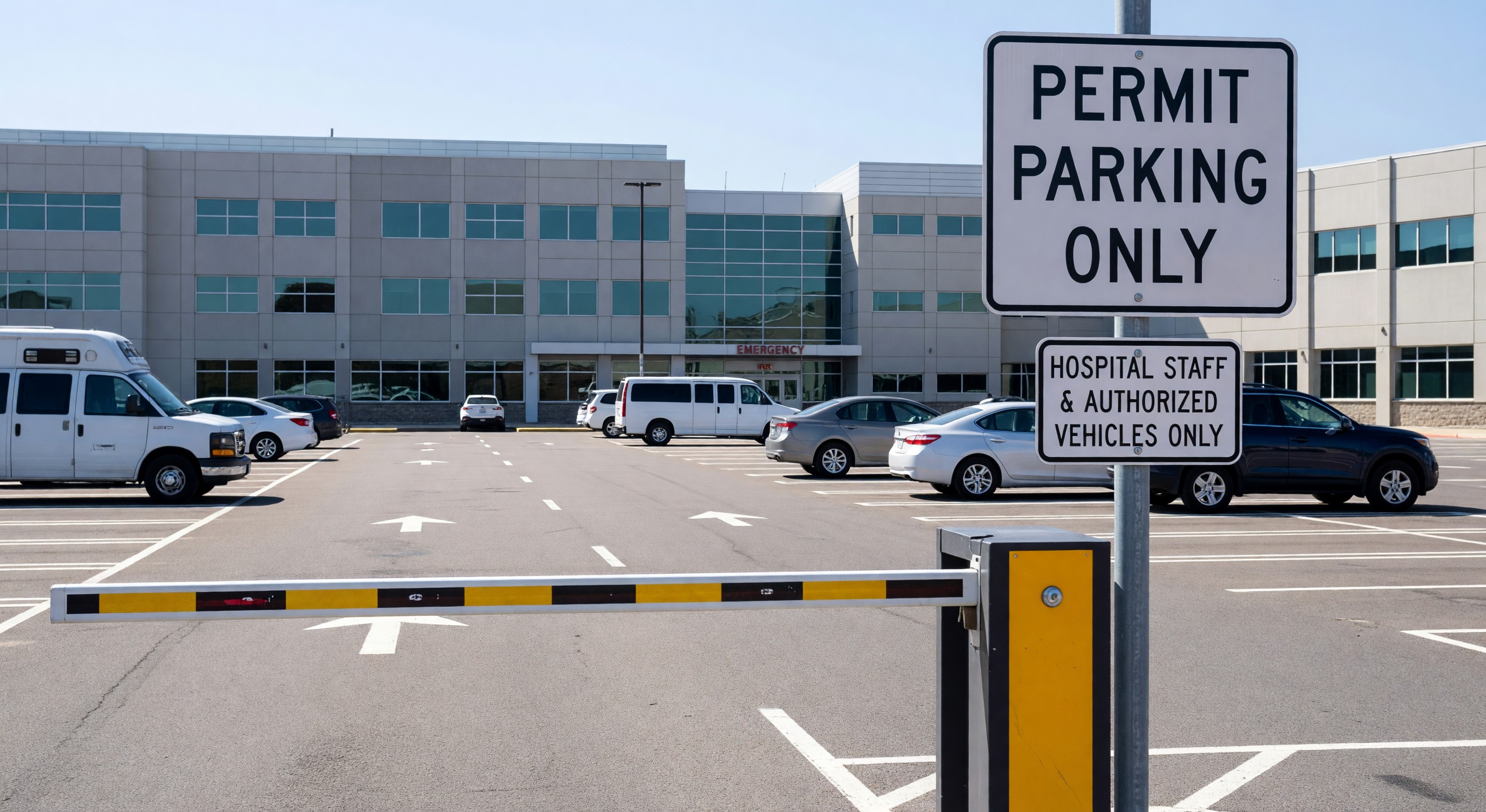 Hospital parking lot with clear permit zone signage and access control barrier gate