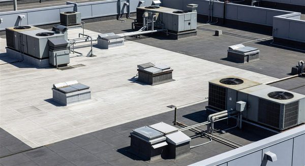 Hospital rooftop showing multiple HVAC units, roof membrane sections, and maintenance access hatches