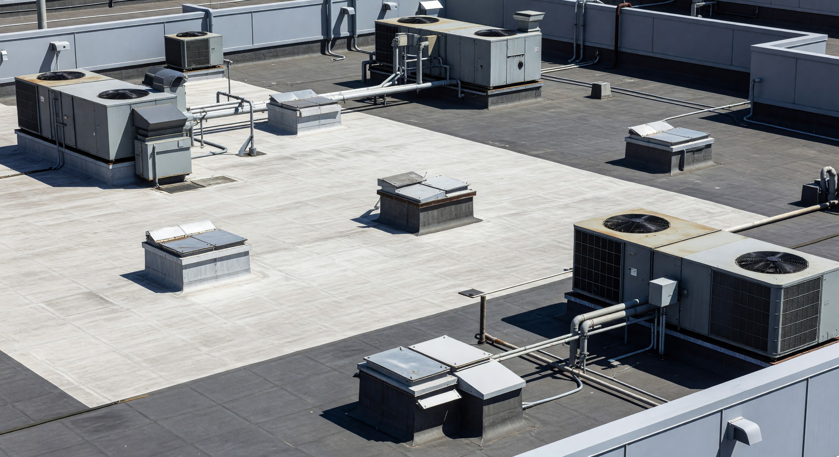 Hospital rooftop showing multiple HVAC units, roof membrane sections, and maintenance access hatches
