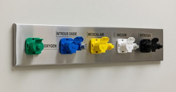 Medical gas outlet panel on hospital wall with labeled connections