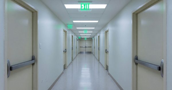 Hospital corridor showing compliant means of egress with exit sign illumination and door hardware