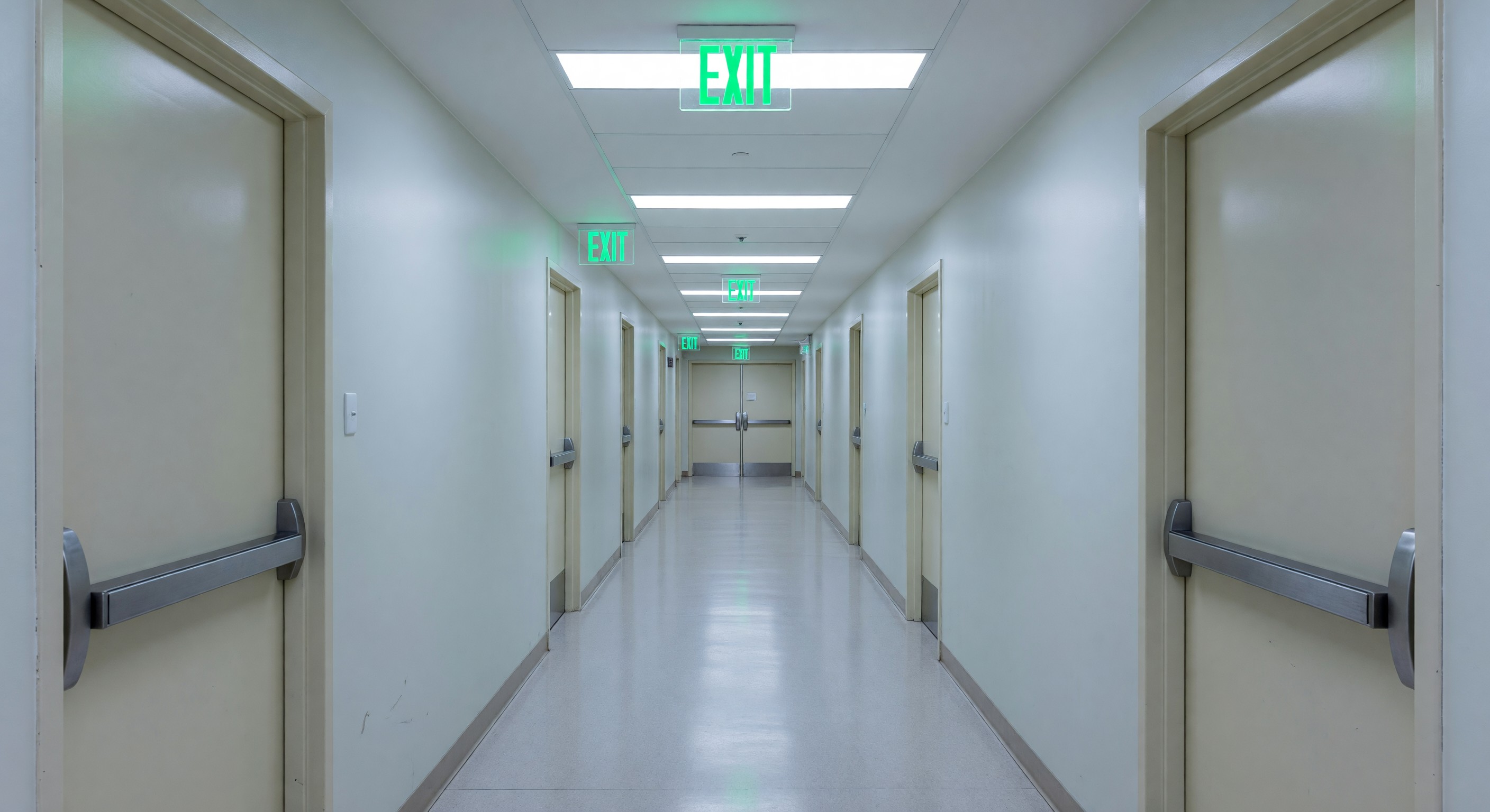 Hospital corridor showing compliant means of egress with exit sign illumination and door hardware