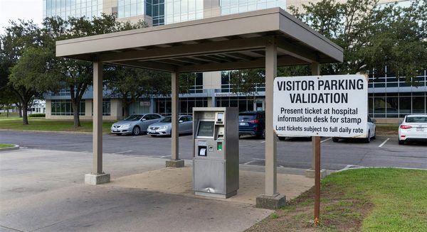Hospital visitor parking entrance with pay station and validation information signage